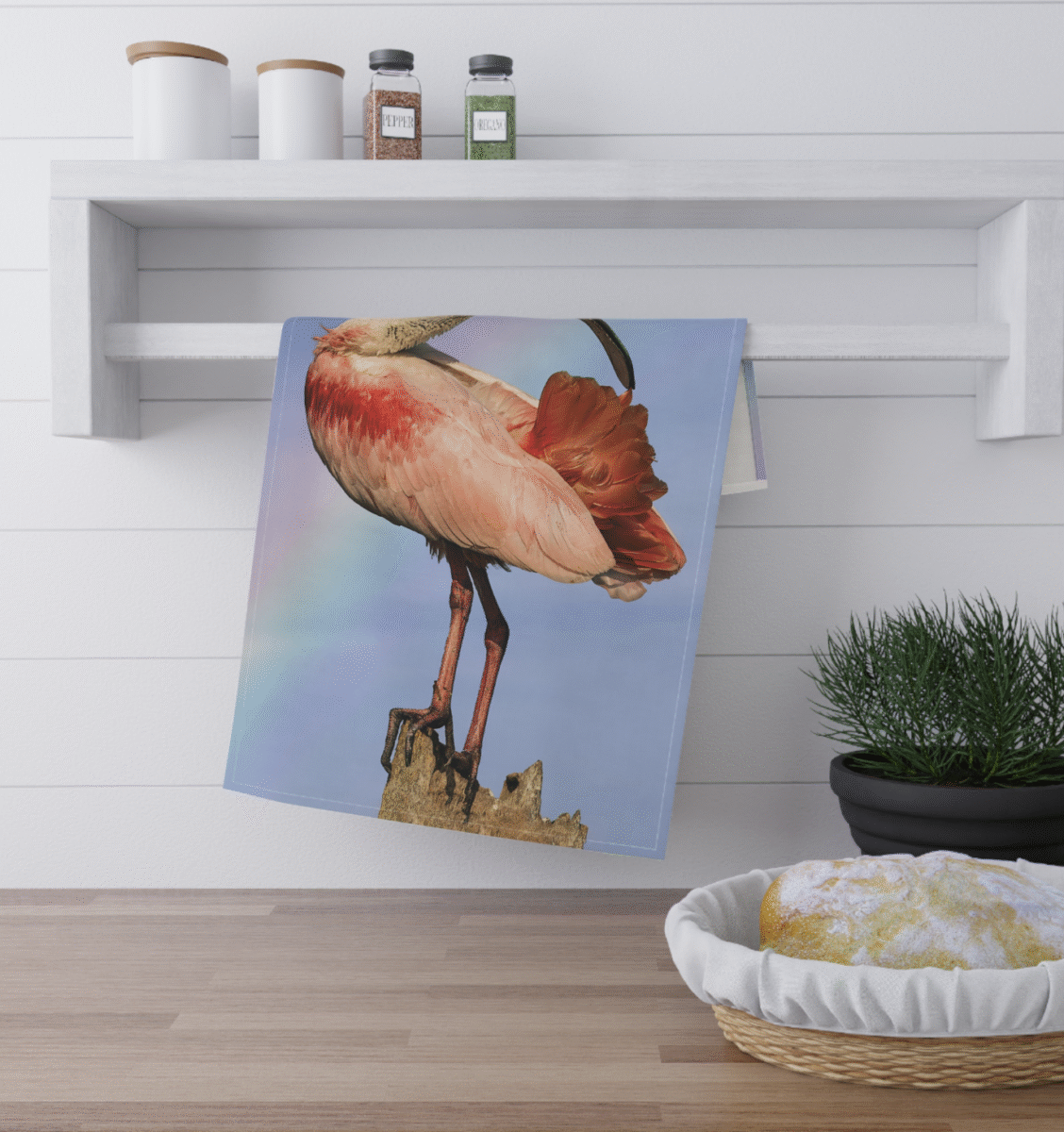 Roseate Spoonbill bird standing on a rock, with pink and white plumage and a long, spoon-shaped beak, against a background of a rainbow-tinted sky.