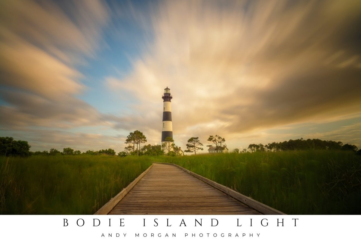 Bodie Island Lighthouse, a tall black and white striped lighthouse, silhouetted against a dramatic and colorful sunset sky with vibrant orange and purple clouds over the Outer Banks coast.