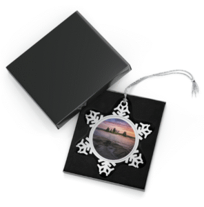 A snowflake-shaped pewter ornament featuring a photograph of the Pumpkin Island Lighthouse on a small island, surrounded by water and a colorful sunset sky.