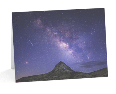 A notecard displaying a photograph of the Milky Way galaxy arcing above the dark silhouette of Mitre Peak under a star-filled night sky, near Fort Davis, Texas.
