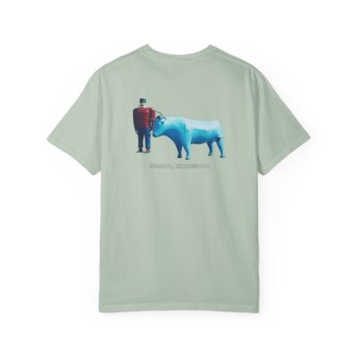 Light green t-shirt featuring a graphic of the Paul Bunyan and Babe the Blue Ox statues in Bemidji, Minnesota. Paul Bunyan is wearing a red and black plaid shirt, and Babe is a large blue ox. The text "BEMIDJI, MINNESOTA" is visible below the statues.