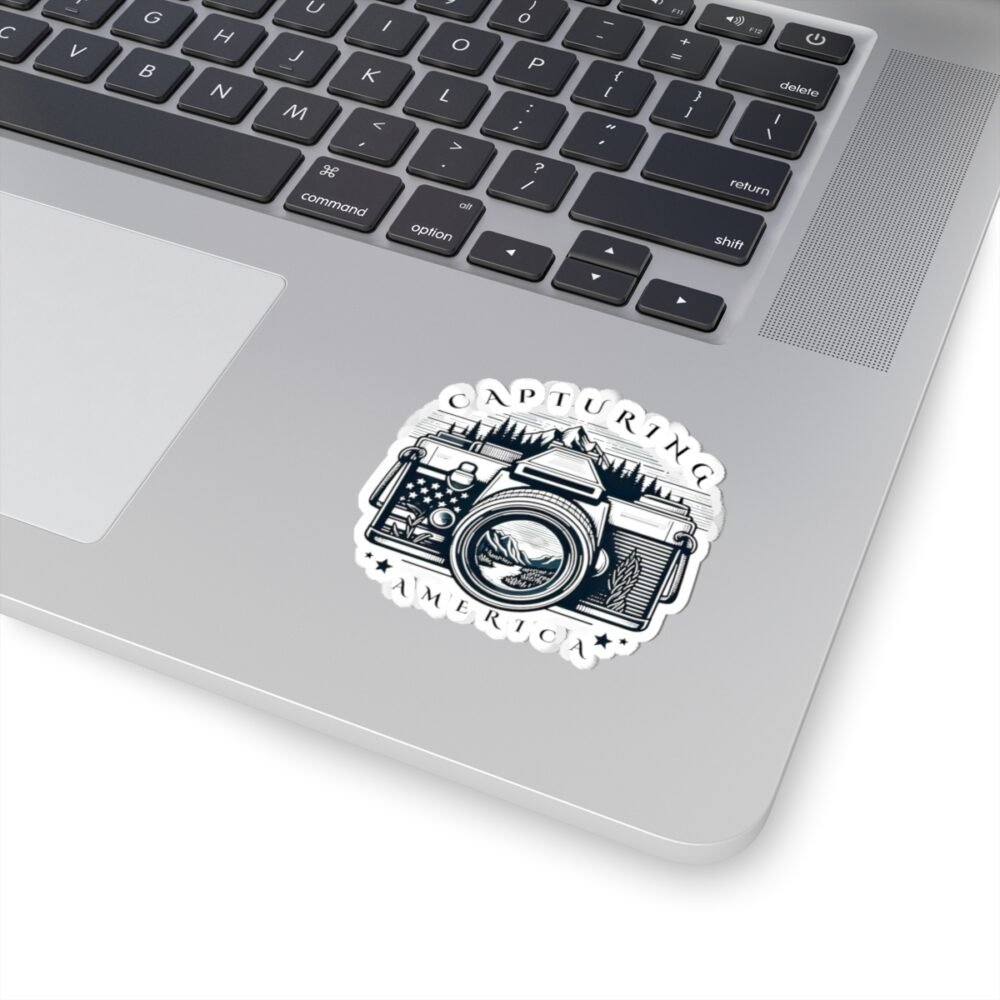 Laptop with a white sticker featuring a vintage camera with "CAPTURING AMERICA" text and mountain landscape.