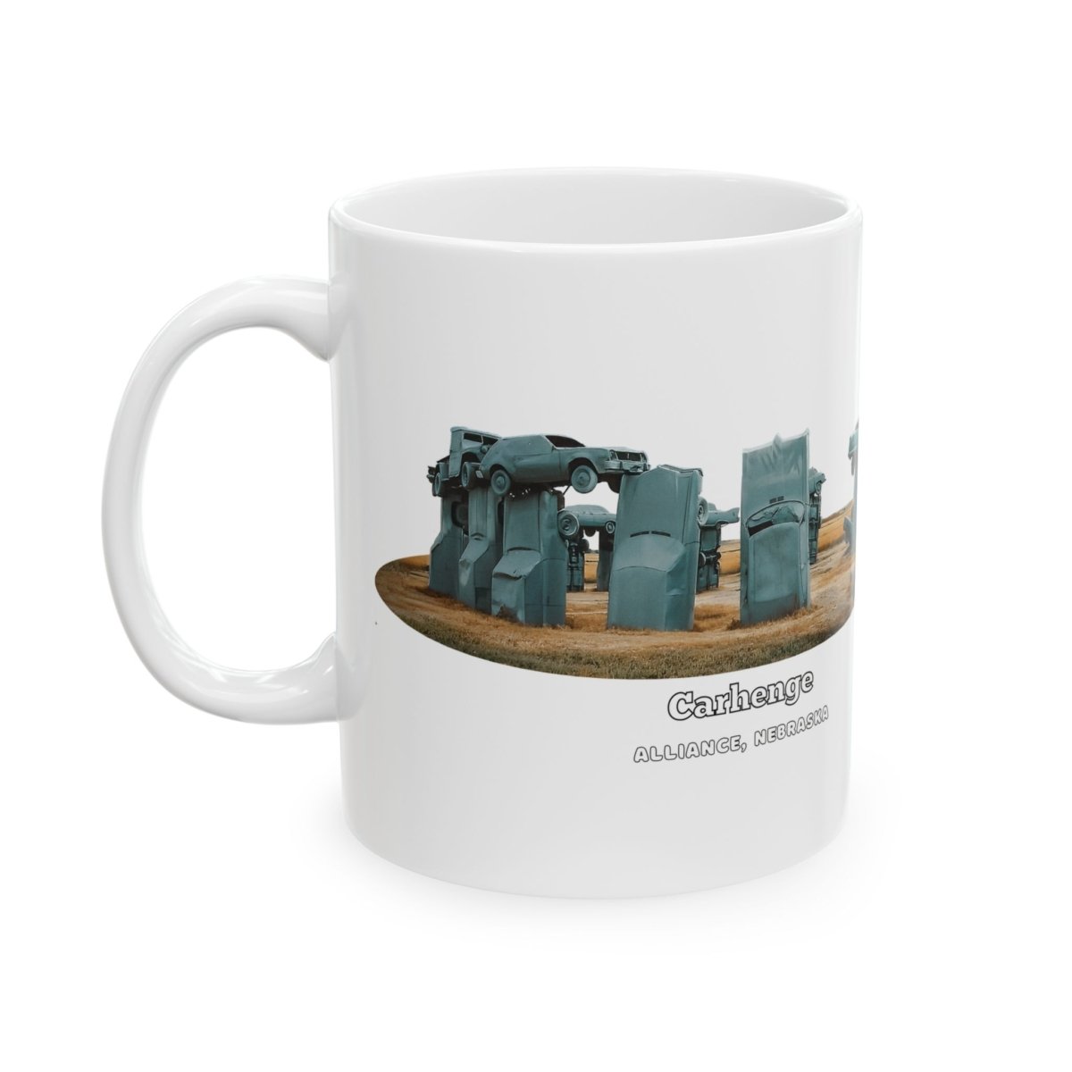 A white ceramic coffee mug with a graphic of Carhenge, a replica of Stonehenge made from vintage gray cars, with text reading "CARHENGE ALLIANCE, NEBRASKA."