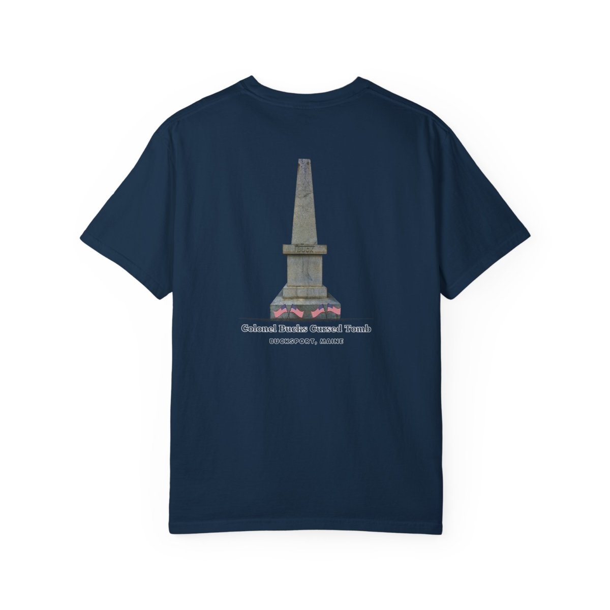 A dark blue t-shirt with a graphic of a tall, grey stone obelisk with a dark stain near the base, and text that reads "Colonel Bucks Cursed Tomb BUCKSPORT, MAINE."