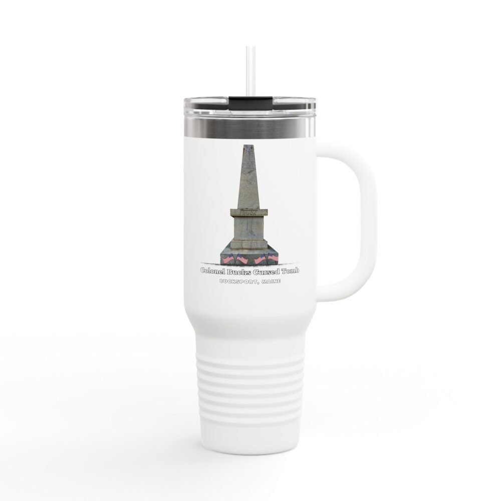 A white insulated travel tumbler with a clear lid and straw, featuring a graphic of a tall, grey stone obelisk with a dark stain near the base, and text that reads "Colonel Bucks Cursed Tomb BUCKSPORT, MAINE."
