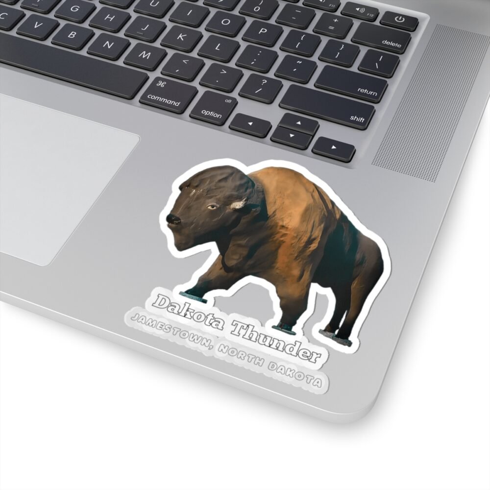 A die-cut vinyl sticker on a laptop, featuring "Dakota Thunder," a large brown bison statue, and "JAMESTOWN, NORTH DAKOTA" text.
