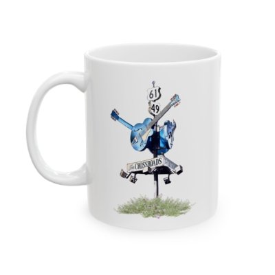 White ceramic coffee mug featuring a blues crossroads sign with a blue guitar and "THE CROSSROADS" text.