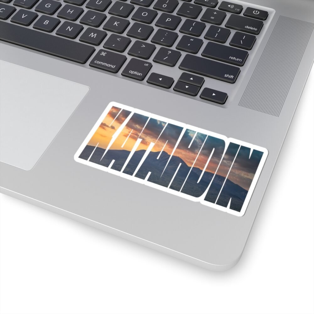 Laptop with a "KATAHDIN" sticker featuring a sunset over a mountainous landscape.