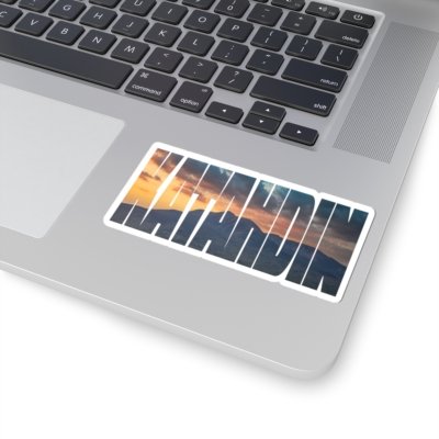 Laptop with a "KATAHDIN" sticker featuring a sunset over a mountainous landscape.