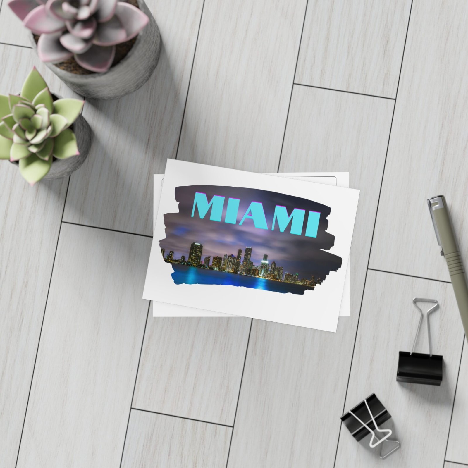 Stack of postcards with a Miami skyline at night, featuring the word "MIAMI" in stylized blue and purple text.