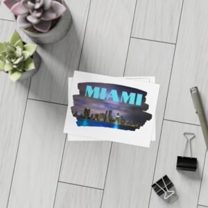 Stack of postcards with a Miami skyline at night, featuring the word "MIAMI" in stylized blue and purple text.