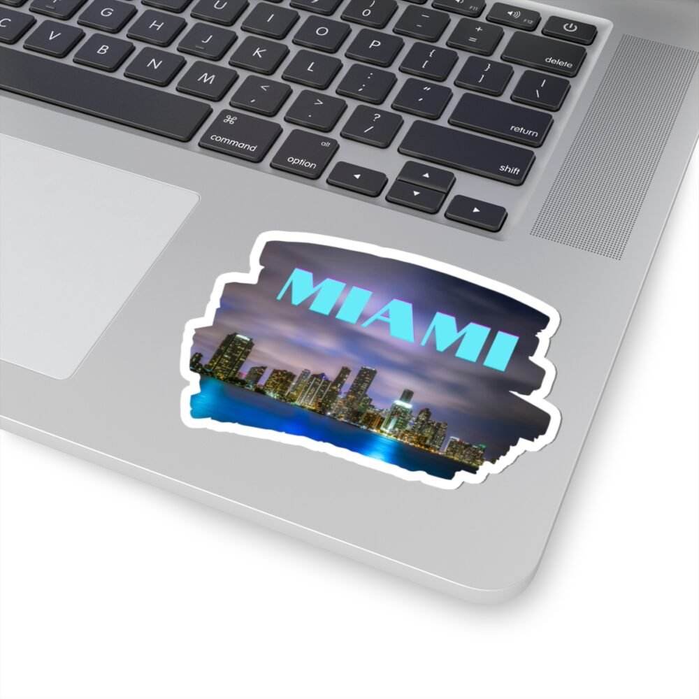 Laptop with a Miami skyline sticker at night, featuring the word "MIAMI" in stylized blue and purple text.