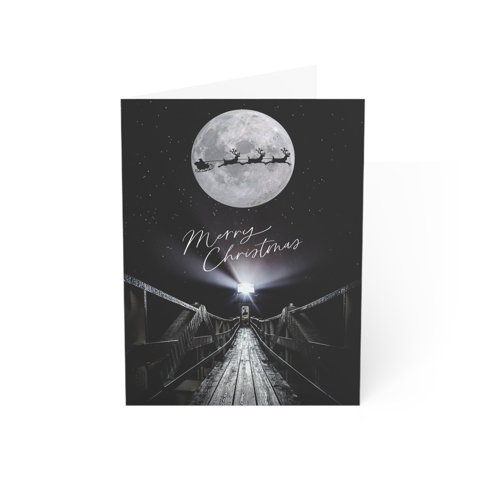 Christmas notecard featuring a high-contrast black-and-white photograph of Marshall Point Lighthouse and its wooden walkway under a full moon, with a silhouette of Santa's sleigh and the text "Merry Christmas" in elegant white script.